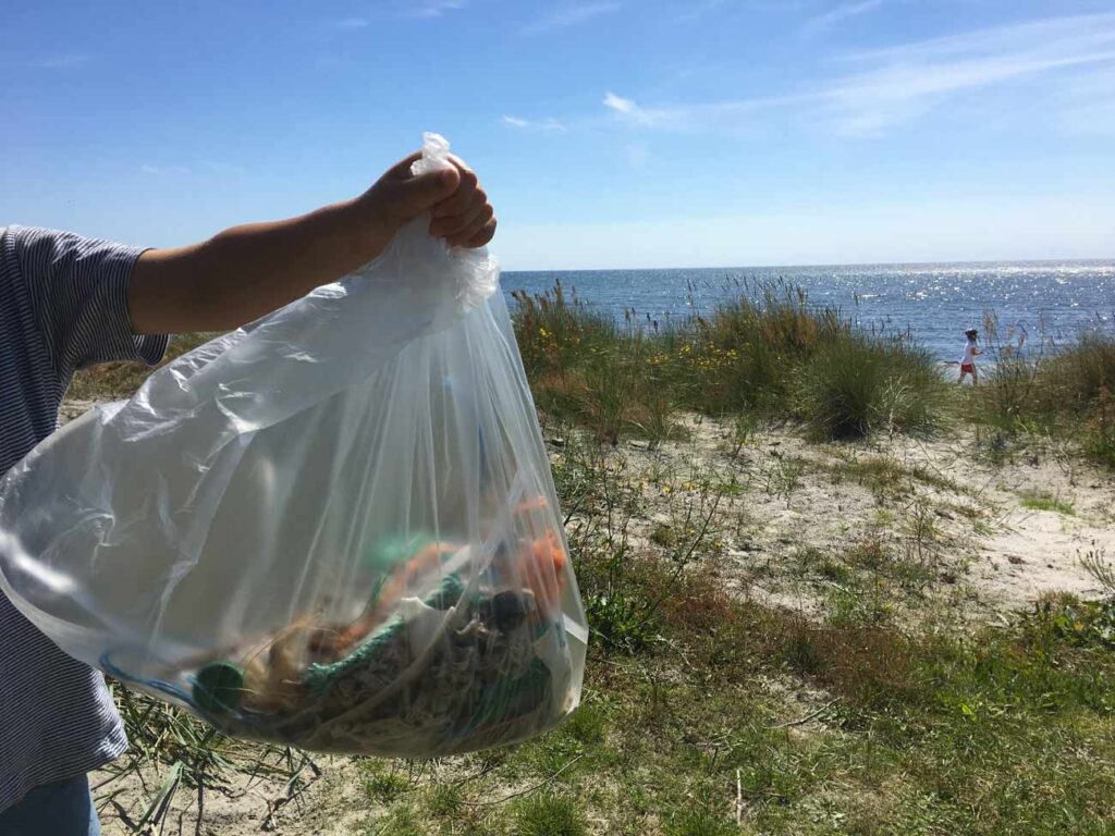 Stolz zeigt mein Sohn den gesammelten Plastikmüll und Abfall, den wir an Bornholms Strand gefunden haben.